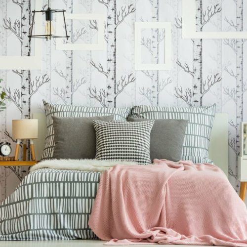Feminine bedroom interior with forest inspired decorations and geometric bedding